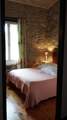 a bedroom with a bed in a stone wall at L'Envolée in Belvianes-et-Cavirac