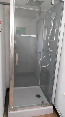 a shower with a glass door in a bathroom at L'Envolée in Belvianes-et-Cavirac