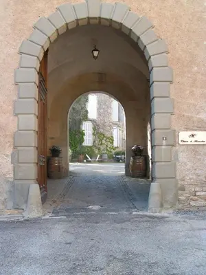 an archway entrance to a building with two pots at Château Moussoulens in Moussoulens