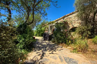a path leading to a stone house with trees at La bergerie du chateau de Fitou in Fitou