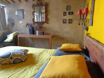 a bedroom with a bed with yellow sheets and a mirror at Loft Ecologique in Villesèque-des-Corbières