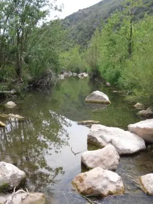 a stream of water with rocks and a mountain at Loft Ecologique in Villesèque-des-Corbières