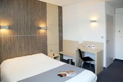 a hotel room with a bed and a desk at The Originals City, Hôtel Le Causséa, Castres in Castres