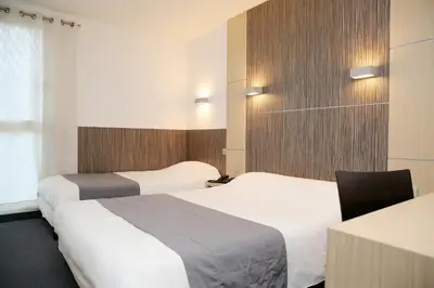 a hotel room with two beds and a desk at The Originals City, Hôtel Le Causséa, Castres in Castres