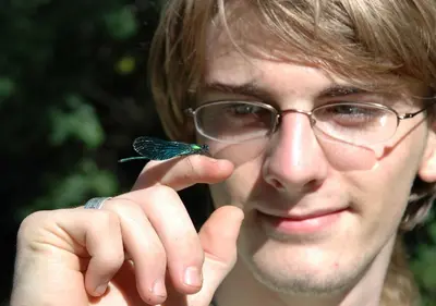 a man with glasses holding a small butterfly on his finger at Gîte rural La Bergerie du Sant in Massaguel