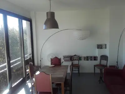 a living room with a table and a red couch at Chambre d'hôtes avec cuisine commune - 5 mns de Narbonne in Cuxac-dʼAude