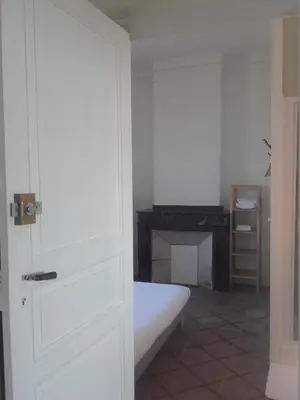 a white bedroom with a bed and a fireplace at Chambre d'hôtes avec cuisine commune - 5 mns de Narbonne in Cuxac-dʼAude