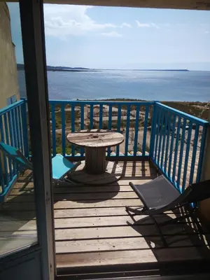 a table and chairs on a deck with a view of the ocean at Fisherman's View in Bages
