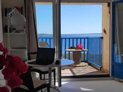 a room with a balcony with a laptop on a table at Fisherman's View in Bages