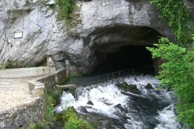 a tunnel in a rock wall with water rushing through it at Palais Cathare in Bélesta