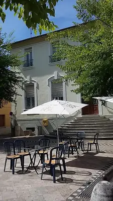 a table and chairs with an umbrella in front of a building at Palais Cathare in Bélesta