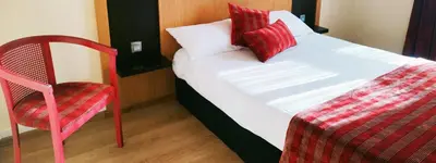 a bed with red pillows and a red chair in a room at Hôtel Restaurant de France in Castelnaudary