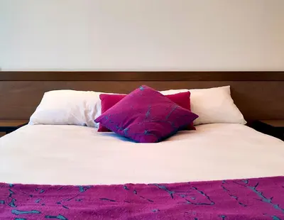 a bed with pink and white pillows on it at Hôtel Restaurant de France in Castelnaudary