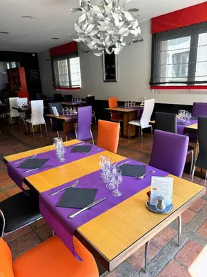 a dining room with tables and chairs and a chandelier at Hôtel Restaurant de France in Castelnaudary