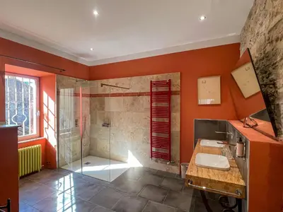a bathroom with orange walls and a shower and a sink at Hôtel d'Alibert in Caunes-Minervois