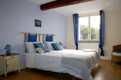 a bedroom with a bed with blue curtains and a window at Jj French Gites in Pécharic-et-le-Py