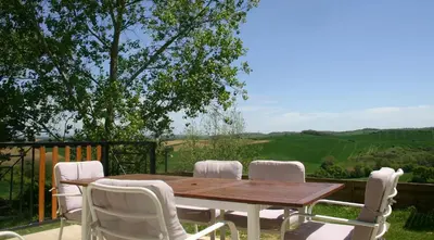 a wooden table and chairs on a deck with a view at Jj French Gites in Pécharic-et-le-Py
