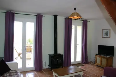 a living room with purple curtains and a wood stove at Jj French Gites in Pécharic-et-le-Py