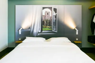 two beds in a room with a window at B&B HOTEL Narbonne 1 in Narbonne