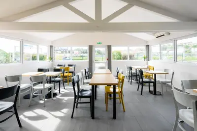 a dining room with tables and chairs and windows at B&B HOTEL Narbonne 1 in Narbonne