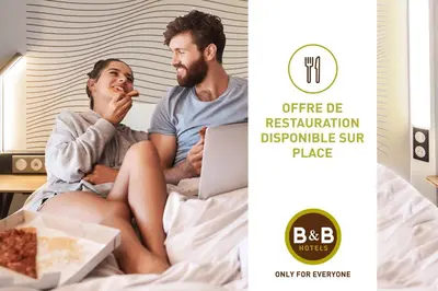 a man and a woman sitting on a bed eating pizza at B&B HOTEL Narbonne 2 in Narbonne