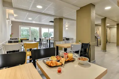 a cafeteria with a table with food on it at B&B HOTEL Narbonne 2 in Narbonne