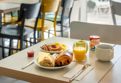a table with two plates of breakfast foods and orange juice at B&B HOTEL Narbonne 2 in Narbonne