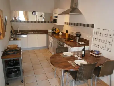 a kitchen with a wooden table and chairs in it at Maison de la Place in Saint-Chinian