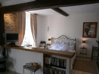 a bedroom with a bed and a desk and a window at Maison de la Place in Saint-Chinian