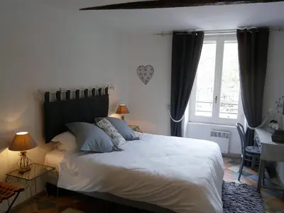 a bedroom with a large white bed with a window at Maison de la Place in Saint-Chinian