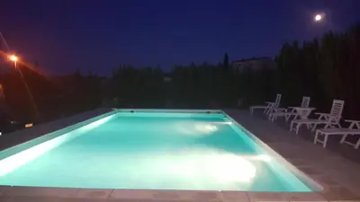 an empty swimming pool at night with white chairs at Nina in Carcassonne