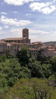 an old building with a clock tower in a city at Maison de Textile Apartment in Montolieu