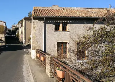 a white house with a fence next to a street at Maison de Textile Apartment in Montolieu