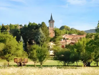 a park with a bench and a church in the background at Maison de campagne avec vue sur la montagne à Puivert. in Puivert