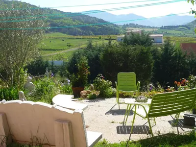 two green chairs and a table in a garden at Le gite de Cristal proche Bugarach in Granès