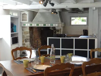 a dining room table with chairs and a kitchen at Le Moulin de l'Abbé in Sorèze