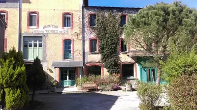 a large brick building with trees in front of it at Le Moulin de l'Abbé in Sorèze