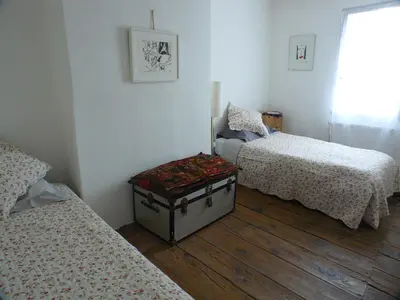 a room with three beds and a trunk on the floor at Nidélice Chambre d'hôtes in Quillan