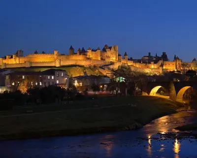 a bridge over a river with a city at night at LOFT SPA - Côté château. in Carcassonne