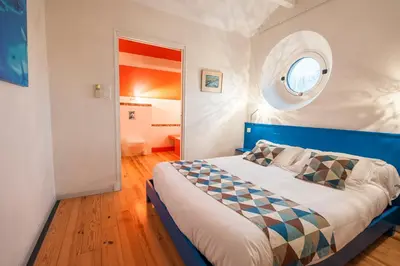 a bedroom with a bed with a blue headboard and a window at Sous les courtines in Carcassonne