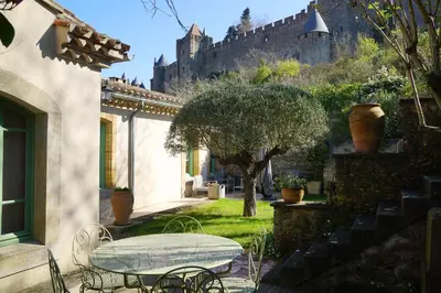 a table and chairs in a yard with a castle in the background at Sous les courtines in Carcassonne