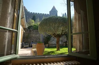 a window view of a yard with a tree and a castle at Sous les courtines in Carcassonne