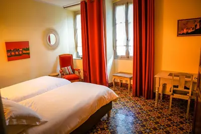 a bedroom with two beds and a table and a chair at Sous les courtines in Carcassonne