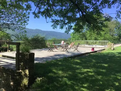 a patio with a table and chairs in the grass at La Bouriotte Gîtes in Labastide-Rouairoux