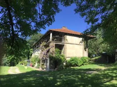 an old building with a balcony on a grass field at La Bouriotte Gîtes in Labastide-Rouairoux