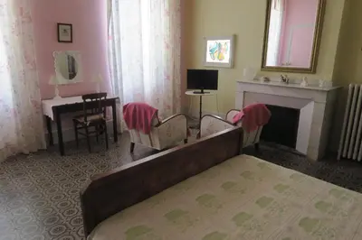 a bedroom with a bed and a fireplace and a desk at Le Domaine de Fraissinet in Ouveillan