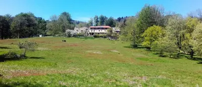 a large field with a house on top of it at La Bouriotte Chambre d'hôtes Bouton D'Or in Labastide-Rouairoux