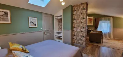 a bedroom with green walls and a bed and a chair at La Glycine Blanche in Pomas