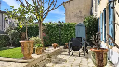 a patio with potted trees and a table and chairs at La Glycine Blanche in Pomas