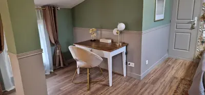 a table and a chair in a room with green walls at La Glycine Blanche in Pomas